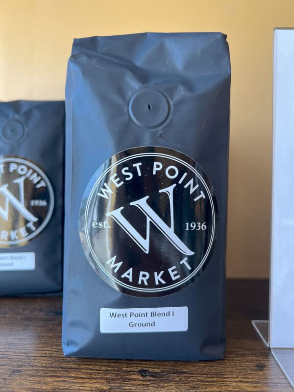 A black bag of WPM Original Coffee Blends sits on a wooden surface, with another similar bag partially visible in the background.