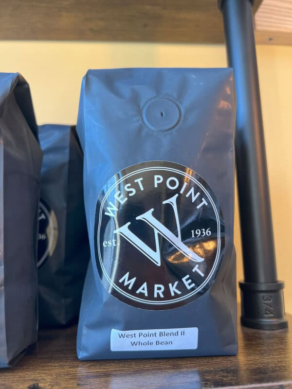 A blue bag of WPM Original Coffee Blends whole bean coffee sits on a shelf, featuring West Point Market’s circular logo and "est. 1936" printed on the front.