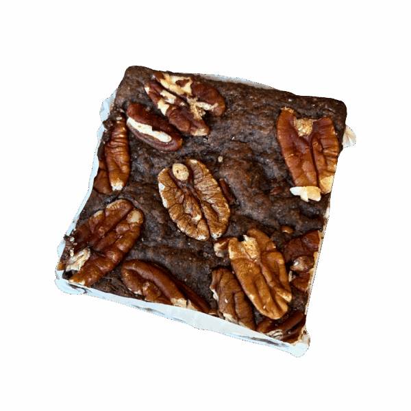 A WPM Original Triple Layer Brownie square, topped with whole pecan halves, sits on white parchment paper against a white background.