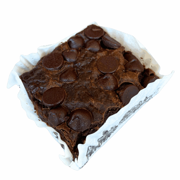 A WPM Original Triple Layer Brownie, square-shaped and topped with large chocolate chips, sits in a crumpled white paper liner against a plain white background.