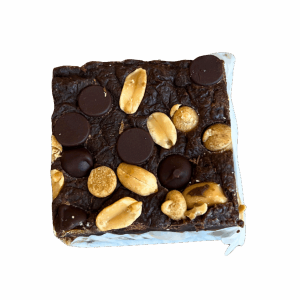 The WPM Original Triple Layer Brownies are square treats topped with whole peanuts and large dark chocolate chips, served on white parchment paper.