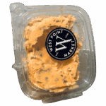 A clear plastic container of orange WPM Cheese Spread with visible herbs and a black circular lid label that reads West Point Market Est. 1936.