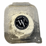 A clear plastic container labeled WPM Cheese Spreads on the lid holds a round portion of herb-speckled cheese.